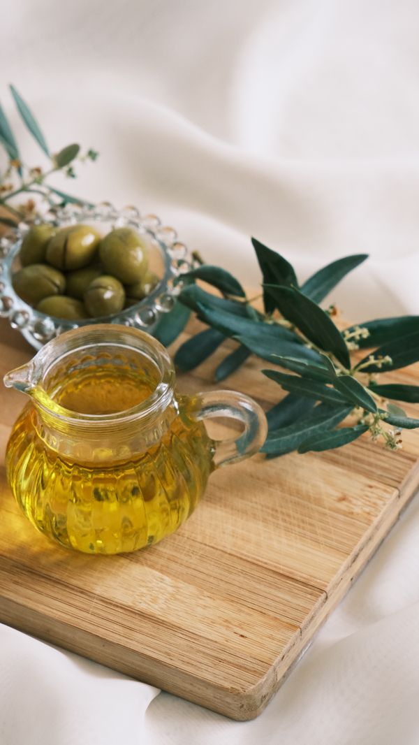 Olio d'oliva in una caraffa di vetro con olive